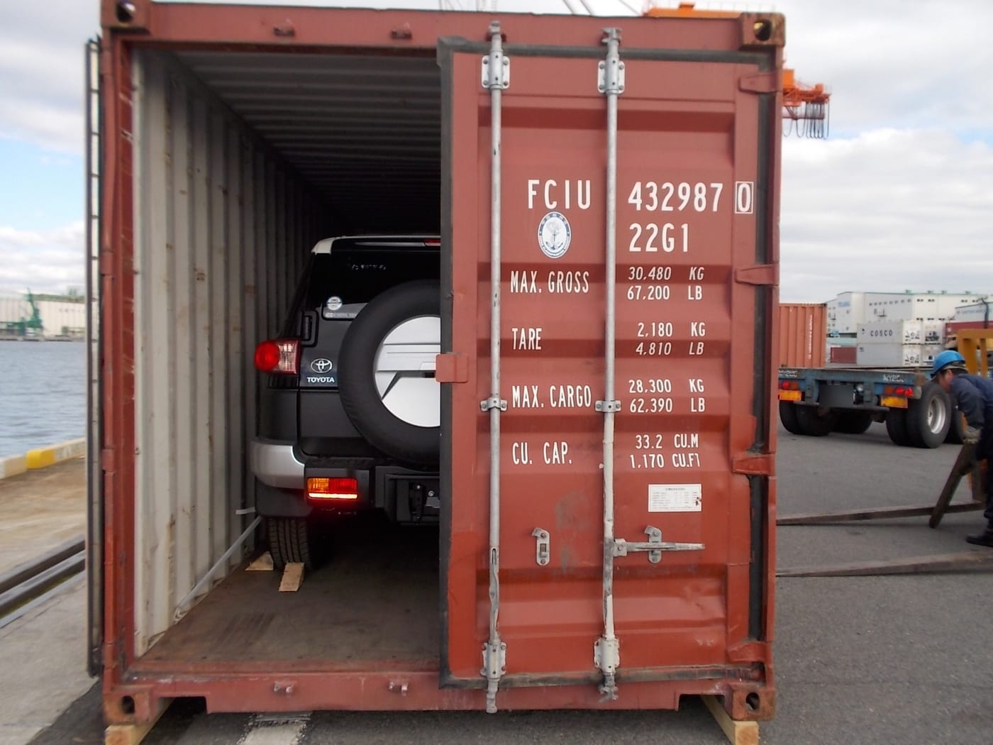 4x4 Toyota chargé dans un conteneur maritime, portes ouvertes au port