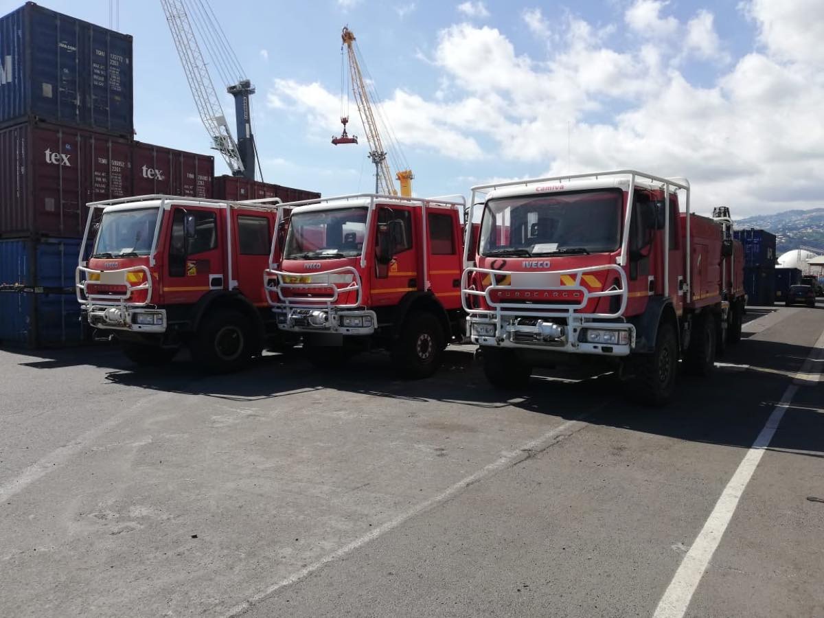 Camions de pompiers alignés sur le quai du port, grues portuaires en arrière-plan